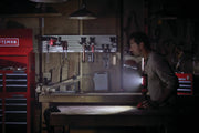 Photo of CRAFTSMAN CMCL050B LED work light illuminating a workshop with tool cabinets and wall-mounted tools.