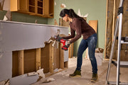 Photo of person using Craftsman CMCS351B cordless reciprocating saw to demolish drywall in a renovation setting.