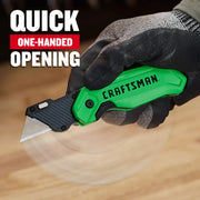 Photo of CRAFTSMAN CMHT10352 utility knife with green handle, shown in a gloved hand demonstrating quick one-handed opening.