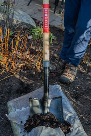 Photo of Craftsman shovel SKU CMXMLTP35329 with wooden handle scooping soil in a garden setting.